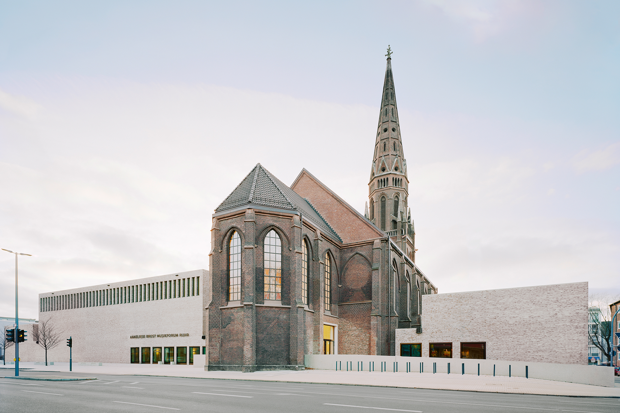 Ansicht auf das profanierte Kirchengebäude flankiert von den Neubauten des Musikforums