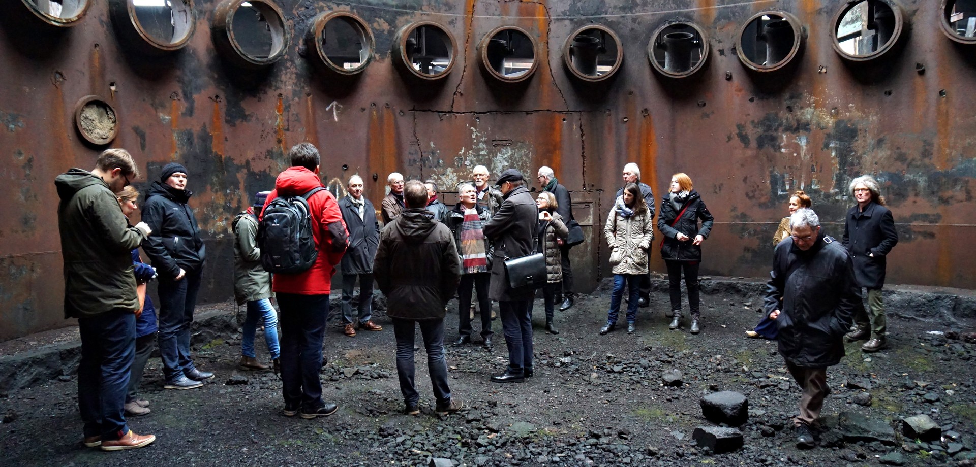 Teilnehmerinnen und Teilnehmer einer Baukulturexkursion in einem Gastank einer Industriebrache im Ruhrgebiet