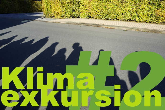Schatten einer Exkursionsgruppe auf der Fahrbahn einer Straße