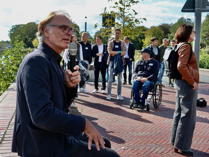 Herr Glück erläutert sitzend auf einer Mauer die weiteren Maßnahmen entlang der Berkelpromenade die realisiert wurden (vergrößerte Bildansicht wird geöffnet)