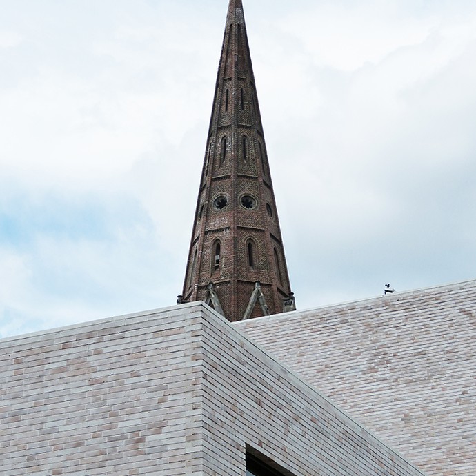 Fassadendetail vom Neubau des Musikforums mit Kirchturm im Hintergrund (vergrößerte Bildansicht wird geöffnet)
