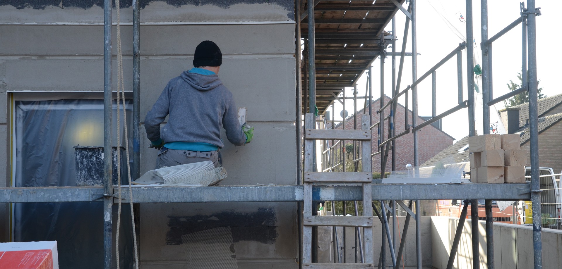 Bauarbeiter auf einem Baugerüst der eine Wand verputzt